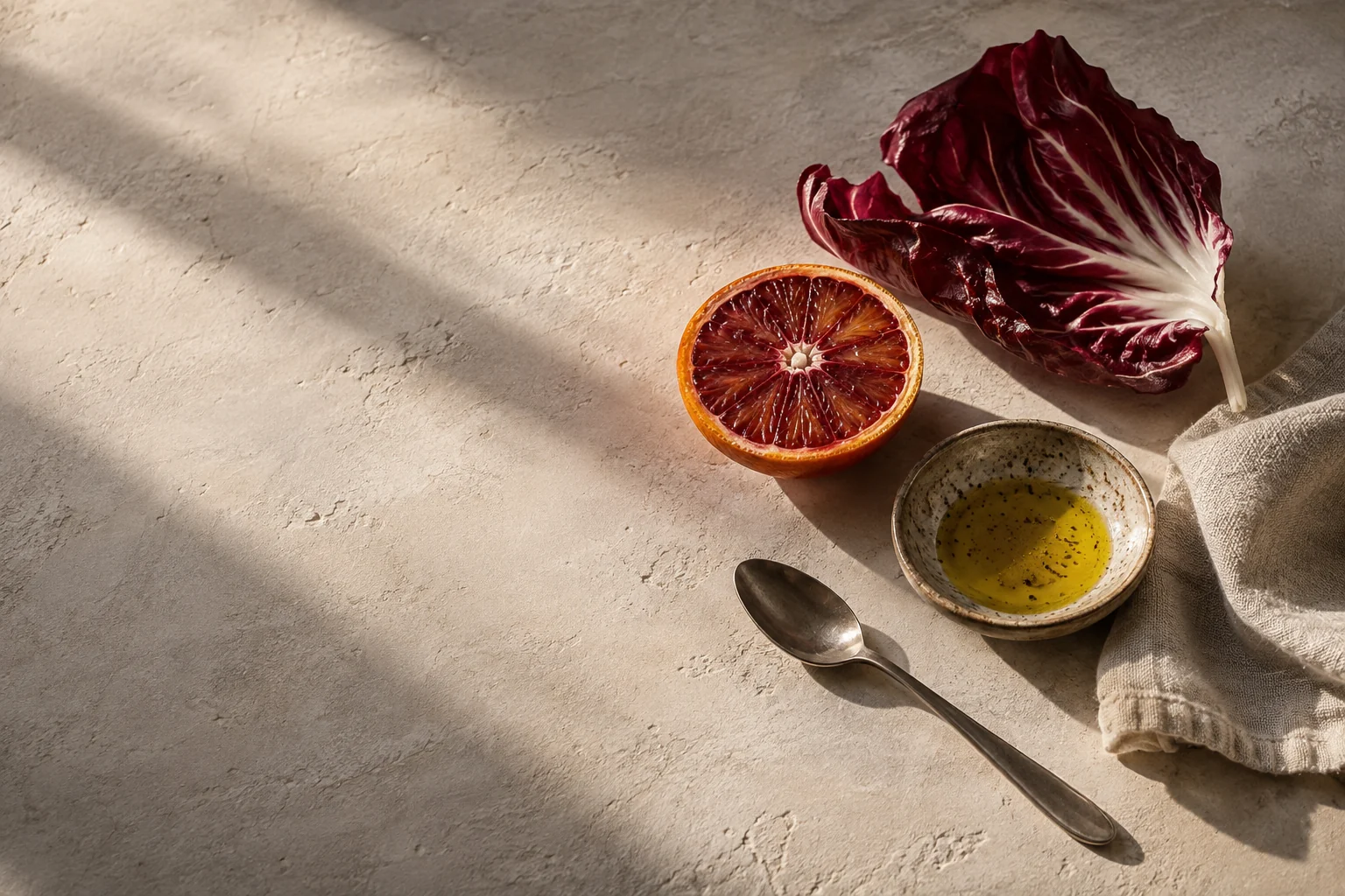Blutorange und Radicchio auf hellem Stein als warmes Food-Stillleben